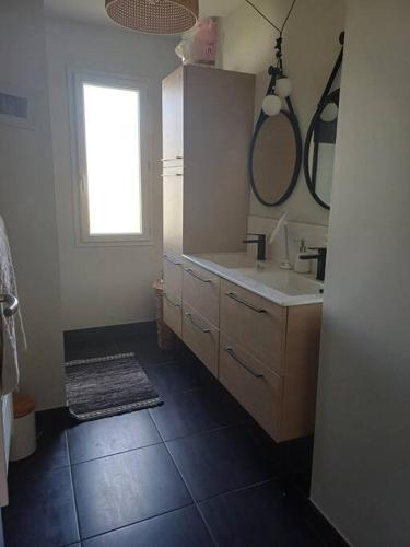 une salle de bain avec un lavabo et un miroir dans l'établissement Maison individuelle, à Neuville-du-Poitou