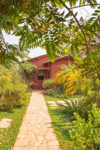 a garden path leading to a red house at Chalés Cores da Mata in Tiradentes