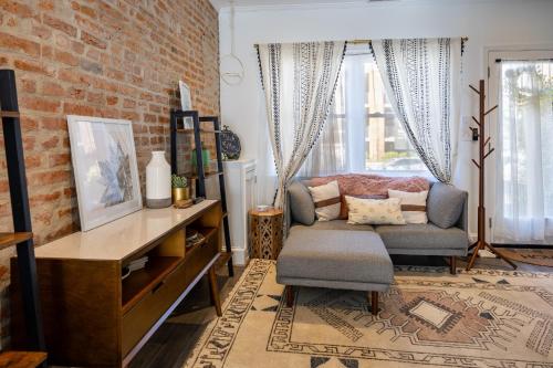 a living room with a couch and a brick wall at Charming 2BR Townhouse with Patio & Parking in DC in Washington