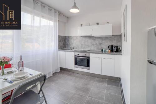 une cuisine avec des placards blancs et une table avec une chaise dans l'établissement Appartement City Mountain, à Cluses