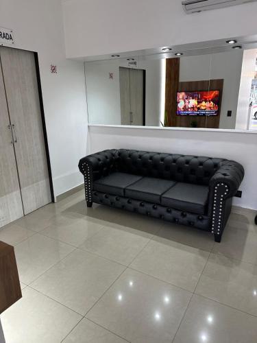 Cette chambre comprend un canapé noir et une télévision. dans l'établissement Hotel Quito, à Buenos Aires