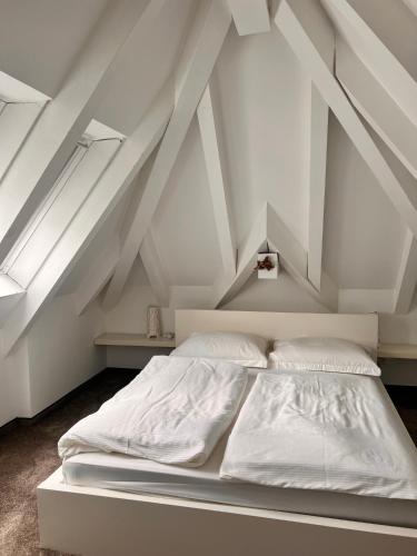 een wit bed in een kamer met een dak bij Penthousetraum im Herzen Merans in Merano