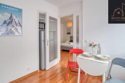 Cette chambre blanche dispose d'une table et d'une chaise rouge. dans l'établissement Appartement Pastel, à Cluses