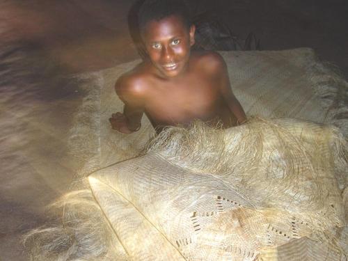 a shirtless man laying on a bed in the water at Beachfront Resort in Luganville