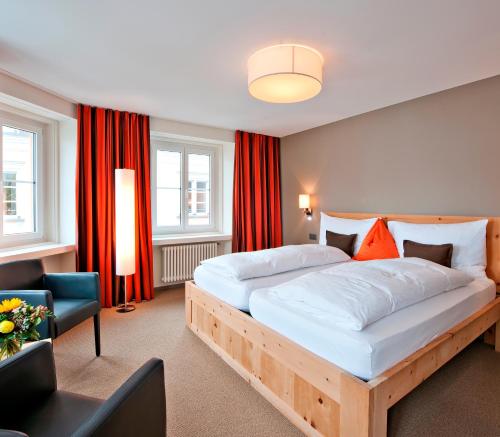 1 dormitorio con 1 cama grande y cortinas rojas en Hotel Donatz, en Samedan