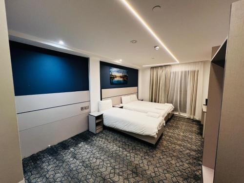 a bedroom with a white bed and a blue wall at Ilford Grand Hotel in Ilford
