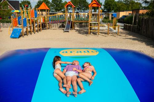 three people laying on a slide at a playground at Vakantiepark duinzicht in Koudekerke