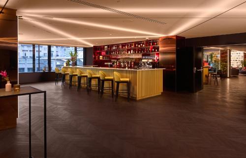 a bar in a restaurant with yellow stools at Cardo Brussels, Autograph Collection in Brussels