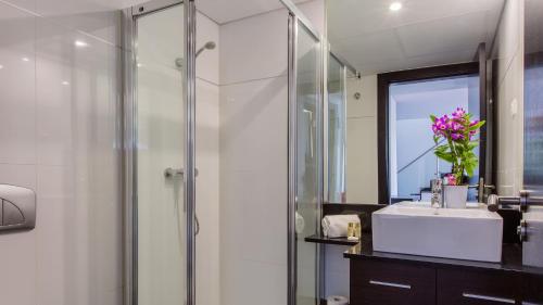 ein Badezimmer mit Dusche, Waschbecken und Spiegel in der Unterkunft Monte Laguna Duplex - Greice Homes in Estibeira