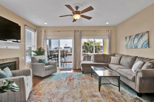 a living room with a couch and a ceiling fan at Pelican Pleasure by Sea Scape Properties in Carolina Beach
