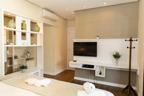 a room with a bed and a tv on a wall at Hospedaria Refúgio das Galés in Bombinhas