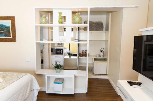 a white book shelf in a bedroom with a bed at Hospedaria Refúgio das Galés in Bombinhas