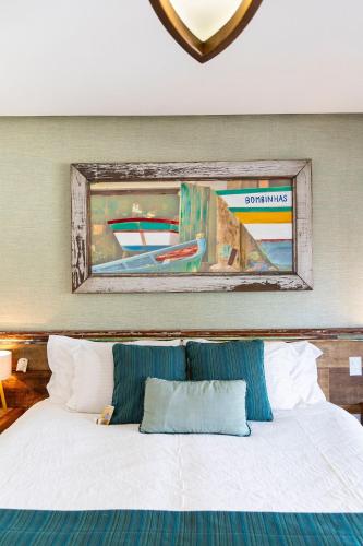 a bedroom with a bed with a painting on the wall at Hospedaria Refúgio das Galés in Bombinhas