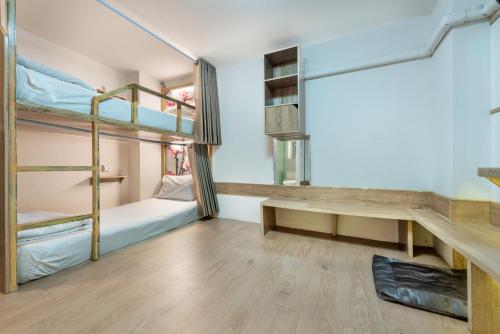 a dorm room with bunk beds and a desk at โรงแรมชิบะรูม นครราชสีมา สาขามหาวิทยาลัยเทคโนโลยีสุรนารี in Nakhon Ratchasima