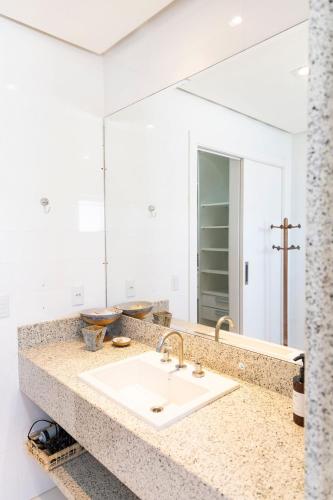 a bathroom with a sink and a large mirror at Hospedaria Refúgio das Galés in Bombinhas