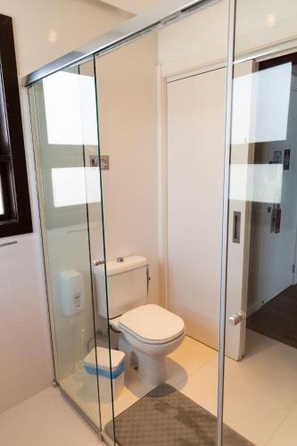 a bathroom with a toilet and a glass shower at Hospedaria Refúgio das Galés in Bombinhas