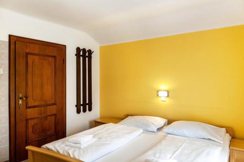 a bedroom with two white beds and a yellow wall at Ferienhaus Sinning in Leogang