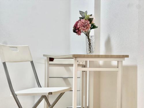 a vase of flowers sitting on a table next to a chair at Nerima house NR0250 in Tokyo