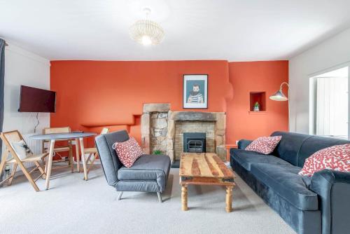 a living room with a blue couch and a fireplace at The Cooperage Garden Apartment - Crail in Crail