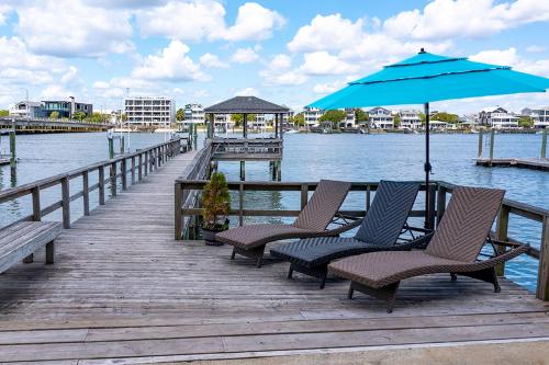 a dock with chairs and an umbrella on the water at The Blue Pearl by Sea Scape Properties in Wrightsville Beach