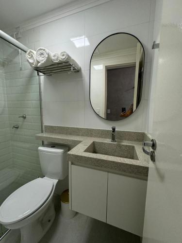 a bathroom with a toilet and a sink and a mirror at Modern apartment near SESC in Franca