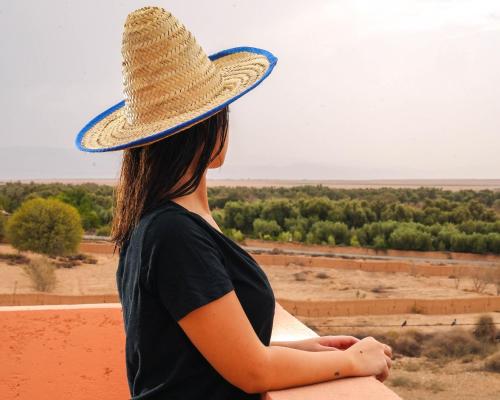 a woman wearing a straw hat looking out at the desert at Sakia Talamanzou in Talamennzou