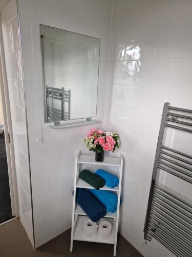 a bathroom with a mirror and a shelf with flowers at Neidpath Inn in Peebles