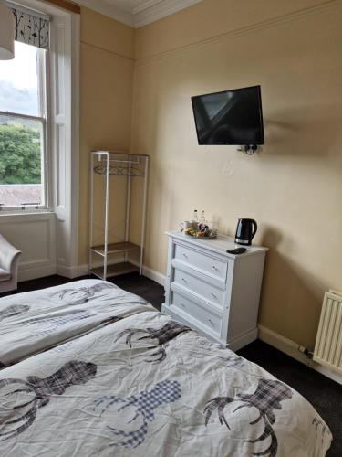 a bedroom with a bed and a tv on the wall at Neidpath Inn in Peebles