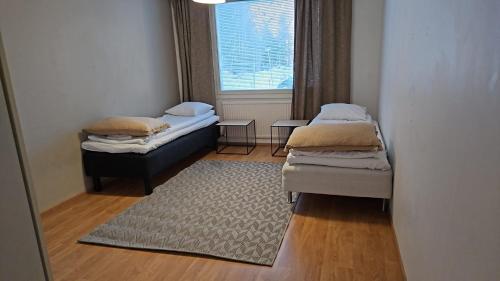 Dos camas en una habitación con alfombra y ventana. en Uitontie Apartment, en Kajaani