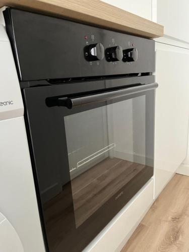 - un four noir avec une porte en verre dans la cuisine dans l'établissement T2 Cosy proche parc de la Hotoie, à Amiens