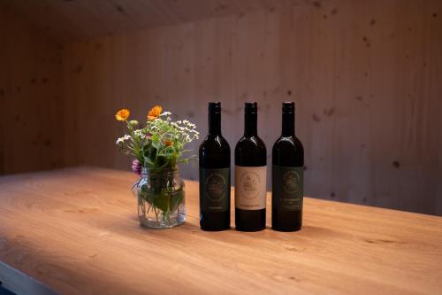 three bottles of wine and a vase of flowers on a table at Haus Kanabe in Schoppernau