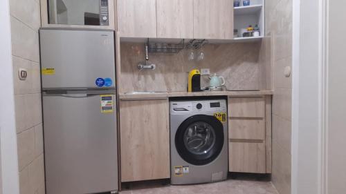 a small kitchen with a refrigerator and a washing machine at Delta Sharm luxury pool view apartment Shahrazad in Sharm El Sheikh