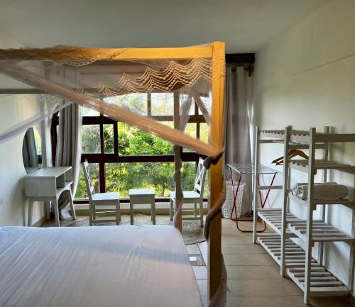 een slaapkamer met een bed en een raam met stoelen bij Golden Sun Studio Apartment in Ukunda