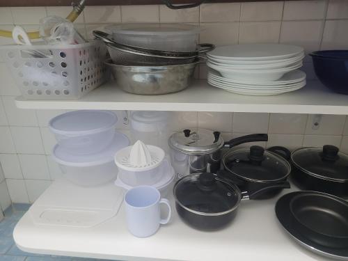 a kitchen counter with plates and dishes on a shelf at Apê aconchegante no Centro da cidade - Cantinho da Bia 2 in Miguel Pereira