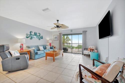 a living room with a blue couch and a tv at Cheerful Pelican on Anna Maria Island in Bradenton Beach