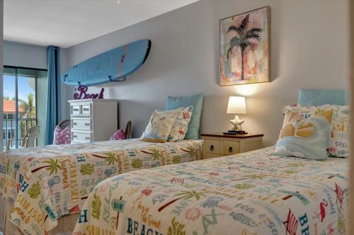 a bedroom with two beds and a surfboard on the wall at Cheerful Pelican on Anna Maria Island in Bradenton Beach