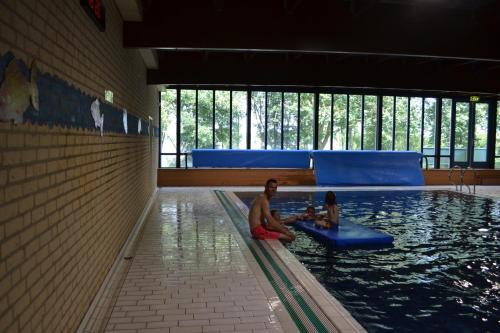 a man and a child sitting in a swimming pool at Comfortabel 6p vakantiehuis met laadpaal in Ewijk
