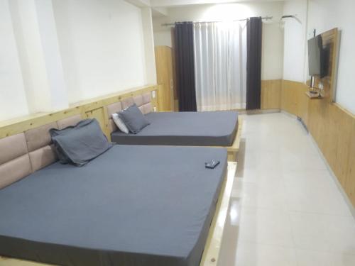 a room with two beds and a tv in it at HOTEL ROSHAN REGENCY By seraj heritage in Shamshi