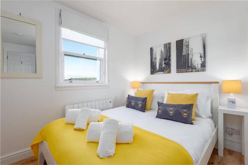 a bedroom with a large white bed with yellow accents at Marine Park No 10 - Elie in Elie
