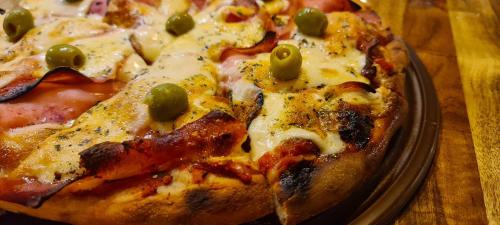 a pizza with green olives on a plate on a table at Criollo Restó & Cabañas in Trevelin