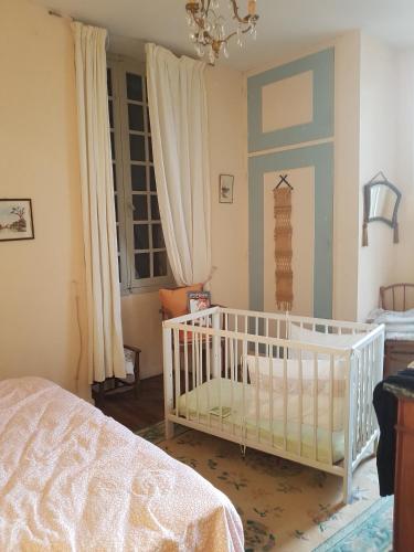 une chambre avec un berceau dans une pièce avec une fenêtre dans l'établissement Le tonnelier, à Limogne-en-Quercy