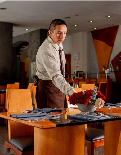 a man standing at a table with a bowl of flowers at El Dorado Hotel in Cuenca