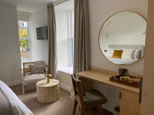 a bedroom with a mirror and a bed and a chair at Somerled House in Portree