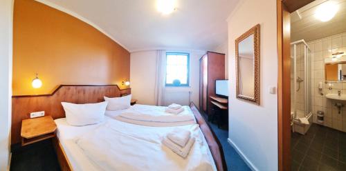 a bedroom with a bed with white sheets and towels at Haus zur Waldbrücke in Marktheidenfeld