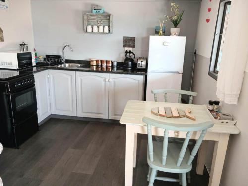 a kitchen with a table and a white refrigerator at Little Camelot in Langebaan