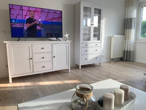 a living room with a television on a white dresser at ZingstUrlauber in Zingst