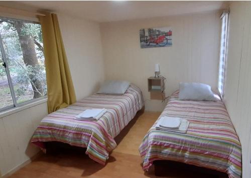 two beds in a room with a window at Cabaña Playa 6 personas Villarrica Pucón in Pucón