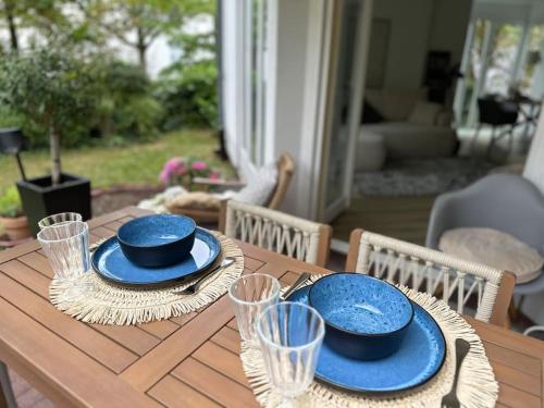 una mesa de madera con placas azules y vasos. en Ruhige Stadtperle mit Garten, en Wiesbaden