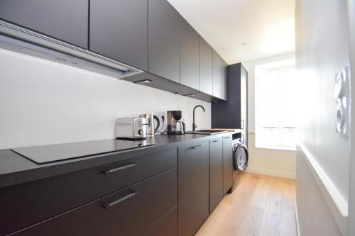 - une cuisine avec des placards noirs et un évier dans l'établissement Appartement 4 pers vue mer au Grand Hôtel, à Saint-Lunaire