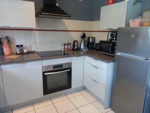 a kitchen with white cabinets and a stainless steel refrigerator at Sur les Rives du Haut Allier in Blassac
